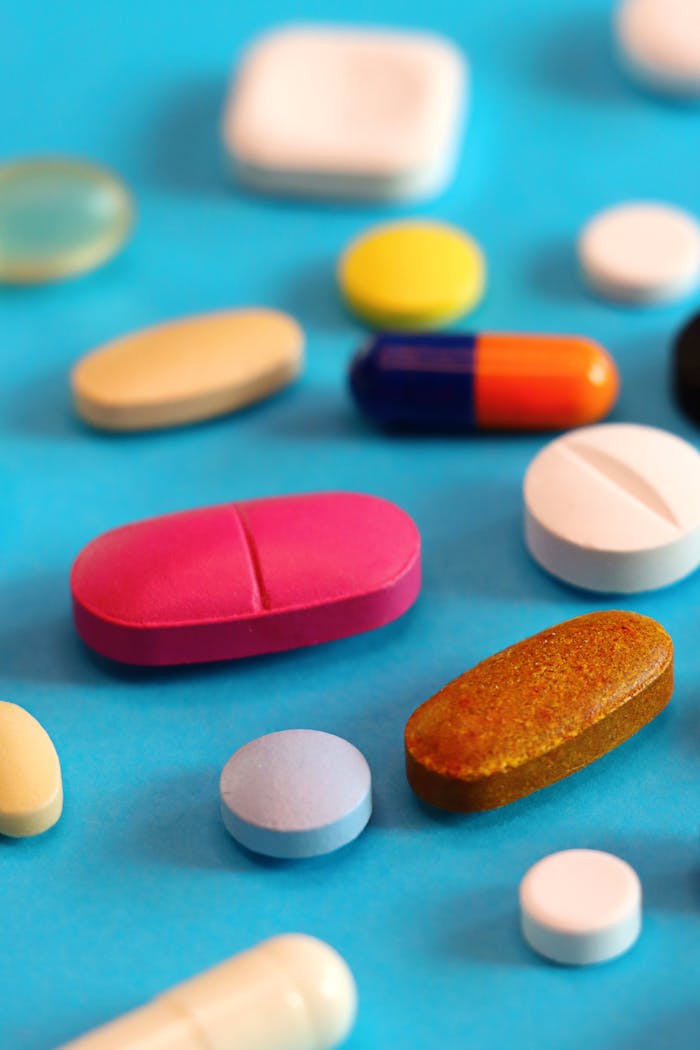 Various colorful pills and tablets scattered on a vibrant blue background.