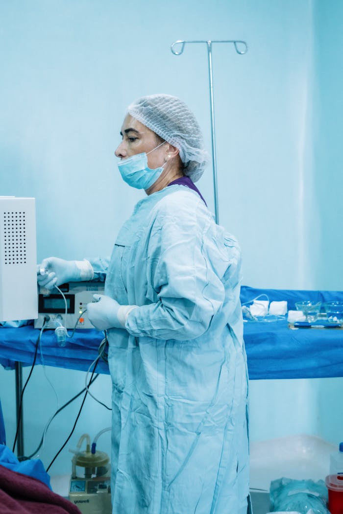 A nurse in surgical scrubs preparing medical equipment in a sterile hospital environment.